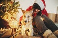 Happy girl in santa hat hugging with cute dog on background of g Royalty Free Stock Photo