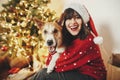 Happy girl in santa hat hugging with cute dog on background of g Royalty Free Stock Photo