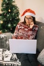 Happy girl with Santa hat looking for presents on laptop Royalty Free Stock Photo