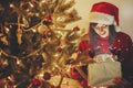 Happy girl in santa hat opening magic Christmas gift box at gold Royalty Free Stock Photo