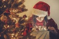 Happy girl in santa hat opening magic Christmas gift box at gold Royalty Free Stock Photo