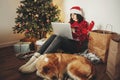 Happy girl in santa hat shopping online on laptop and sitting wi Royalty Free Stock Photo