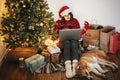 Happy girl in santa hat shopping online on laptop and sitting wi Royalty Free Stock Photo