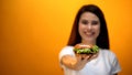 Happy girl showing hamburger to camera, satisfied client of fast food restaurant