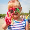 Happy girl shows sign victory with holi paint