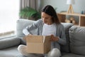 Happy girl sit on couch unpack cardboard box Royalty Free Stock Photo