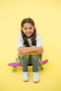 Happy girl sit on penny board on yellow background. Little child smile with long hair on skateboard. Beauty salon. Style Royalty Free Stock Photo