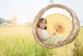 Happy girl sits in wicker swing among the golden rice fields