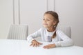 happy girl sitting at empty white glass table in new modern apartment with copy space Royalty Free Stock Photo