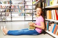 Happy girl sitting on floor near bookshelf Royalty Free Stock Photo