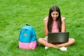 Happy girl sitting on green grass with laptop. Start up. child playing computer game. back to school. education online Royalty Free Stock Photo