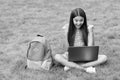 happy girl sitting on green grass with laptop. Start up. child playing computer game. back to school. education online Royalty Free Stock Photo