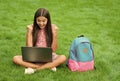 happy girl sitting on green grass with laptop. Start up. child playing computer game. back to school. education online Royalty Free Stock Photo