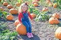 Happy girl sitting on pumpkin at farm field patch Royalty Free Stock Photo