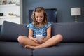 Happy girl sitting on sofa and using mobile phone in living room Royalty Free Stock Photo