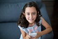 Happy girl sitting on sofa and using mobile phone in living room Royalty Free Stock Photo