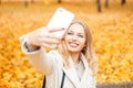 Happy girl with a smile doing selfie in a fall day against