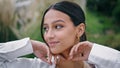 Happy girl smiling in green nature portrait. Cheerful latina woman touching face Royalty Free Stock Photo