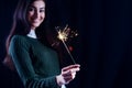 Happy girl smiling and holding a sparkling firework in her hand.