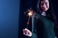 Happy girl smiling and holding a sparkling firework in her hand.