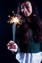 Happy girl smiling and holding a sparkling firework in her hand.