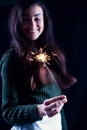 Happy girl smiling and holding a sparkling firework in her hand.