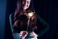 Happy girl smiling and holding a sparkling firework in her hand.