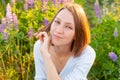 Happy girl smiling outdoor. Beautiful young brunete woman resting on summer field with blooming wild flowers green