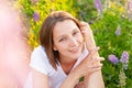 Happy girl smiling outdoor. Beautiful young brunete woman resting on summer field with blooming wild flowers green