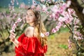 Happy girl in the spring garden peach in red dress Royalty Free Stock Photo