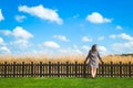 Happy girl stand with wood fence in the green field under blue cloud sky. Beautiful landscape. Royalty Free Stock Photo