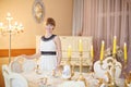 Happy girl stands next to classic white table with