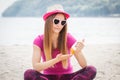 Happy girl in straw hat and sunglasses using sun lotion, sun protection on beach Royalty Free Stock Photo