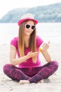 Happy girl in straw hat and sunglasses using sun lotion, sun protection on beach Royalty Free Stock Photo