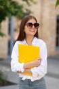 Happy girl student with a yellow folder in his hands. Exams, optimistic startup. Future achievements and ambitions