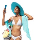 Happy girl in summer beach holiday wearing bikini, blue sun hat and pareo holding beach bag and using mobile phone isolated in Royalty Free Stock Photo
