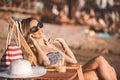 Happy girl in a swimsuit talking on a mobile phone on the beach