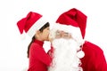 Happy Girl telling wish in Santa Claus`s ear