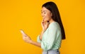 Happy girl texting on cellphone over yellow background Royalty Free Stock Photo