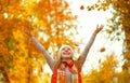 Happy girl throws up autumn leaves in park for walk outdoors