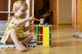 Happy girl toddler hitting wooden hammer on colored balls early development ecological toy Royalty Free Stock Photo