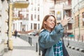 Happy girl traveler in casual clothes walks in the old town and takes a photo landscape on a smartphone. Beautiful tourist in a