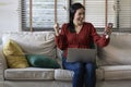 Happy girl using a laptop and smart phone. Happy young woman using phone, browsing mobile device app, playing game, on sofa. Royalty Free Stock Photo