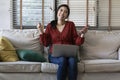 Happy girl using a laptop and smart phone. Happy young woman using phone, browsing mobile device app, playing game, on sofa. Royalty Free Stock Photo