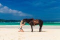 Happy girl walking with horse on a tropical beach