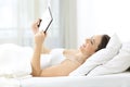 Girl watching tv online with a tablet in the bed Royalty Free Stock Photo