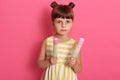 Happy girl with water ice cream looking directly at camera with serious facial expression, standing with two hair buns, wearing Royalty Free Stock Photo