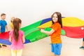 Happy girl waving colorful parachute with friends Royalty Free Stock Photo