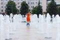 Happy girl in wet dress roller skates in fountain in summ