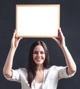 Happy girl in white shirt with poster in frame overhead. Smiling woman holding blank billboard